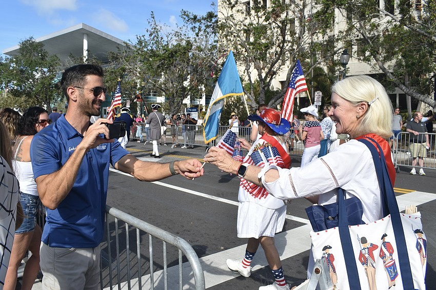 Jake Coad takes a flag from Liz Taft of Daughters of the American Revolution.