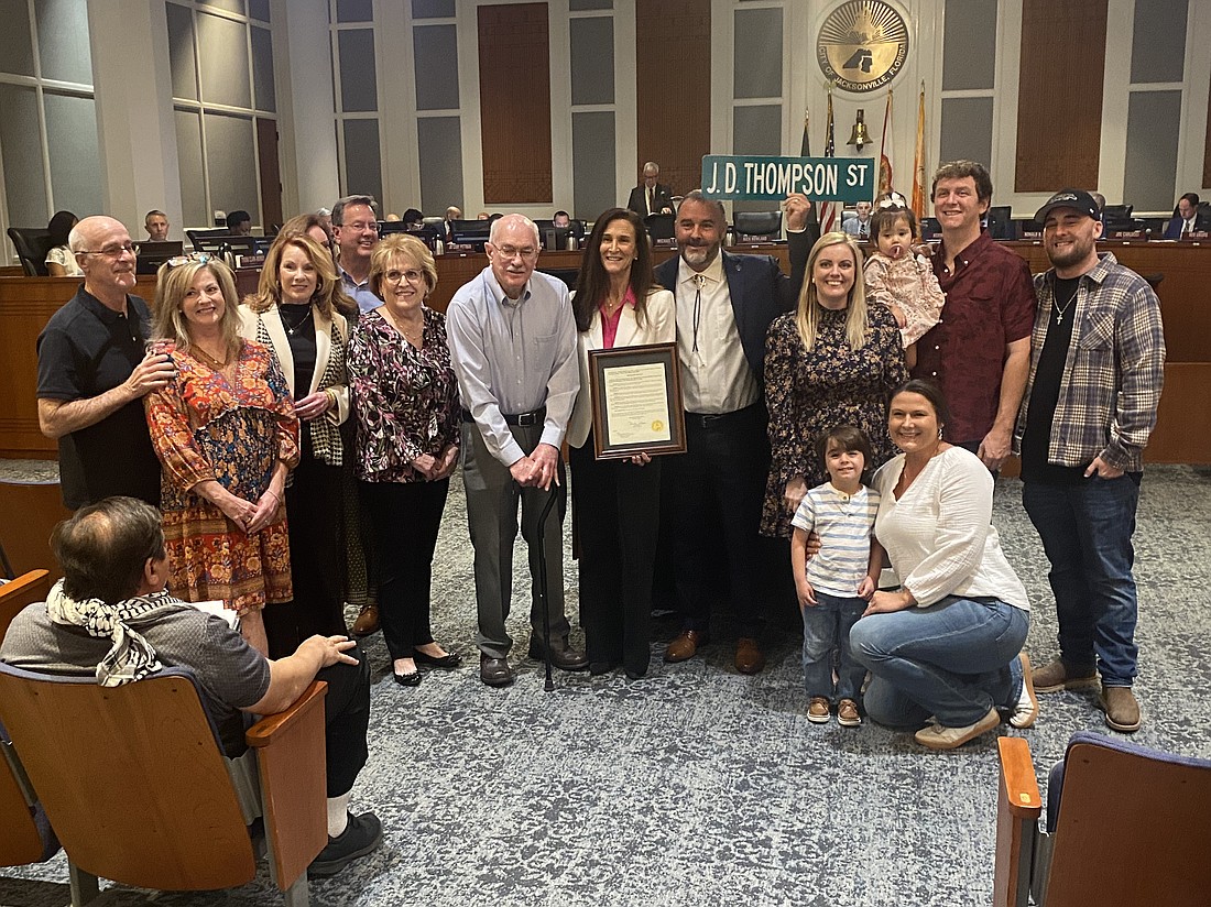 Former Jacksonville City Electric lineman J.D. Thompson, in light blue shirt, is honored Nov. 12 with a City Council proclamation commending him for his 1967 rescue of fellow lineman Randall Champion. The rescue, which prompted creation of training methods that continue to be practiced today, was the subject of a Pulitzer Prize-winning photo republished internationally. Standing to Thompson's left is Vickie Cavey, JEA CEO and managing director. To her left, holding sign, is Council member Mike Gay. Also shown are family members of Thompson.