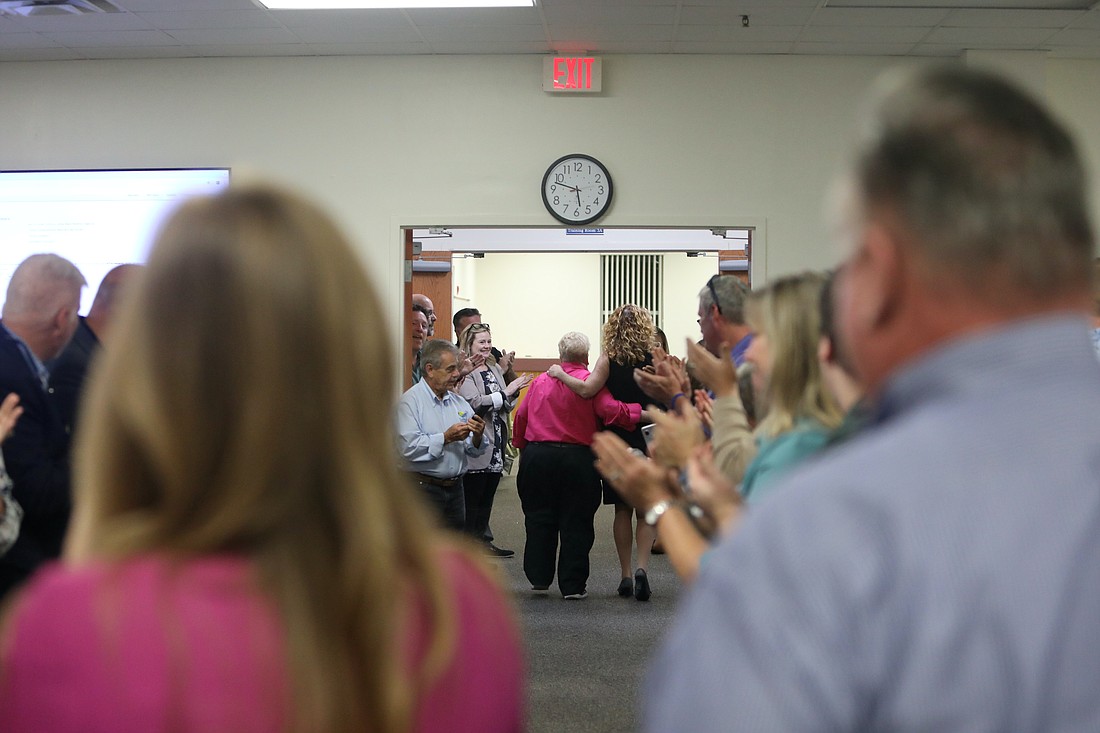 Flagler County Schools staff clap as board members Cheryl Massaro and Colleen Conklin walk out of the workshop room together. Photo by Brent Woronoff