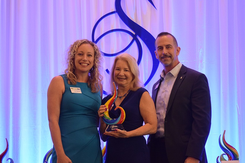 Brittany Lamont, the president and CEO of the Lakewood Ranch Business Alliance, congratulates Lee Kotwicki of the State College of Florida, Sarasota-Bradenton for winning the Above and Beyond award, after Bryan Boudreaux with the Bank of Tampa presents the award.