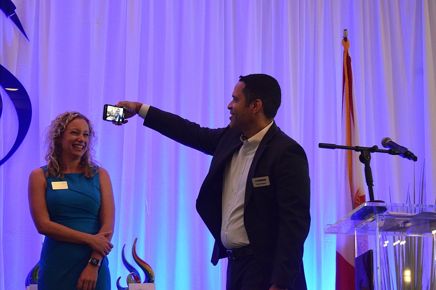 Brittany Lamont, the president and CEO of the Lakewood Ranch Business Alliance, laughs as Networking King Henry Decoo commemorates his win with a selfie of him and the guests at the Sandies.