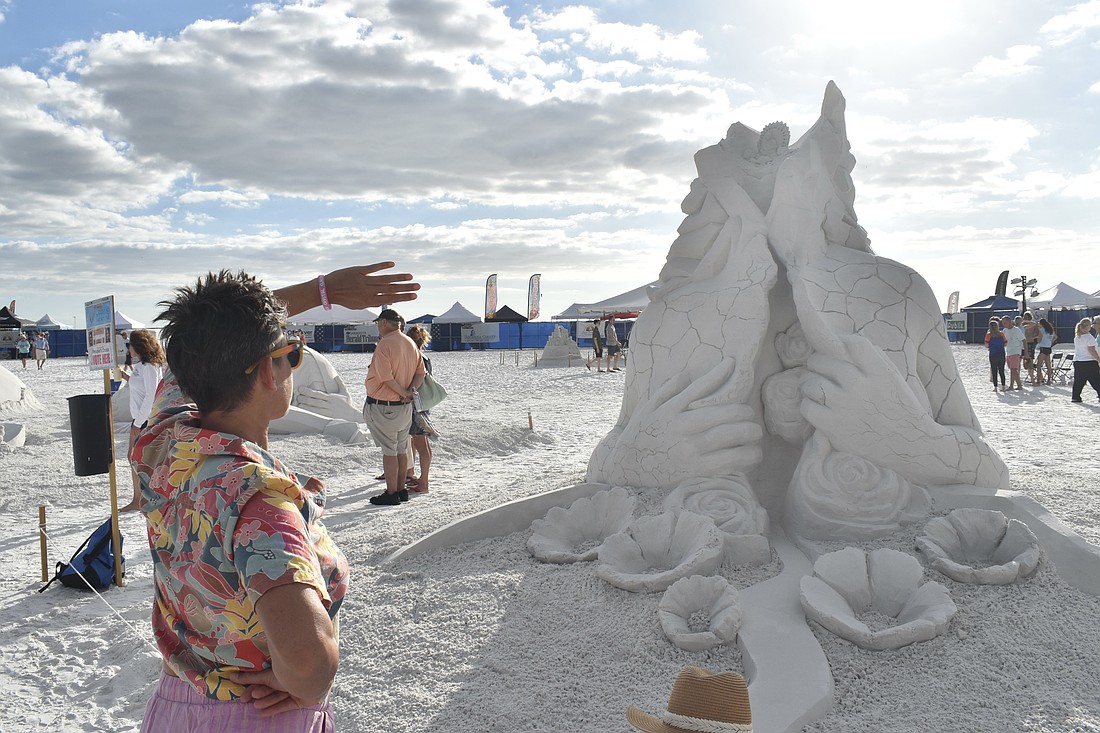 Morgan Rudloff looks at "Peace Within" after the sculpture's head collapsed, and the artists finished it off with a crown during the Siesta Key Crystal Classic sand sculpting.