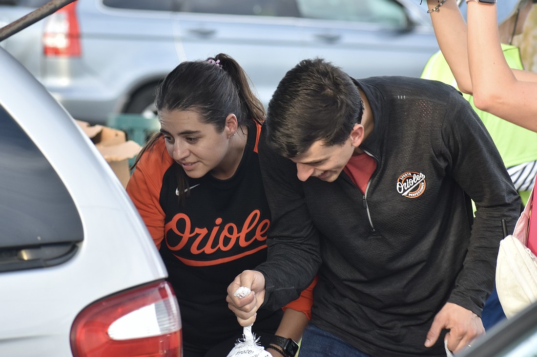 Tori Atencio and Juan Sanches place a turkey in a trunk.