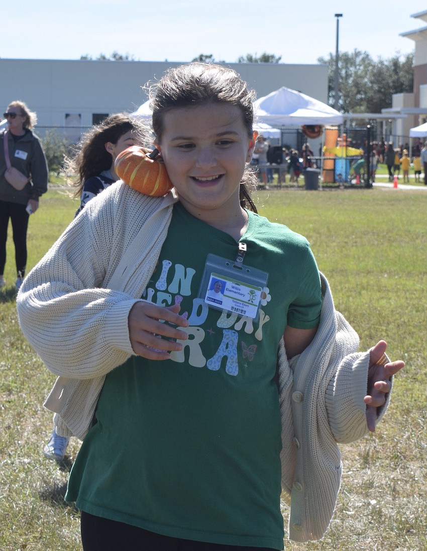 Fifth grader Tatiana Ebert balances the pumpkin between her shoulder and neck to safely carry it to the cone and back.