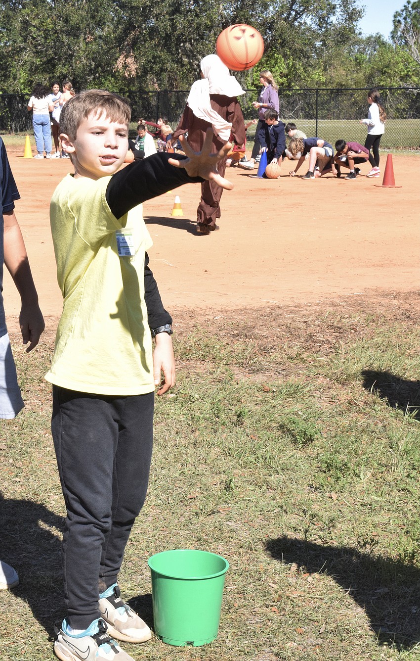 Fifth grader Finn Heffernan tosses a ball into a bucket to earn a third point for his team.