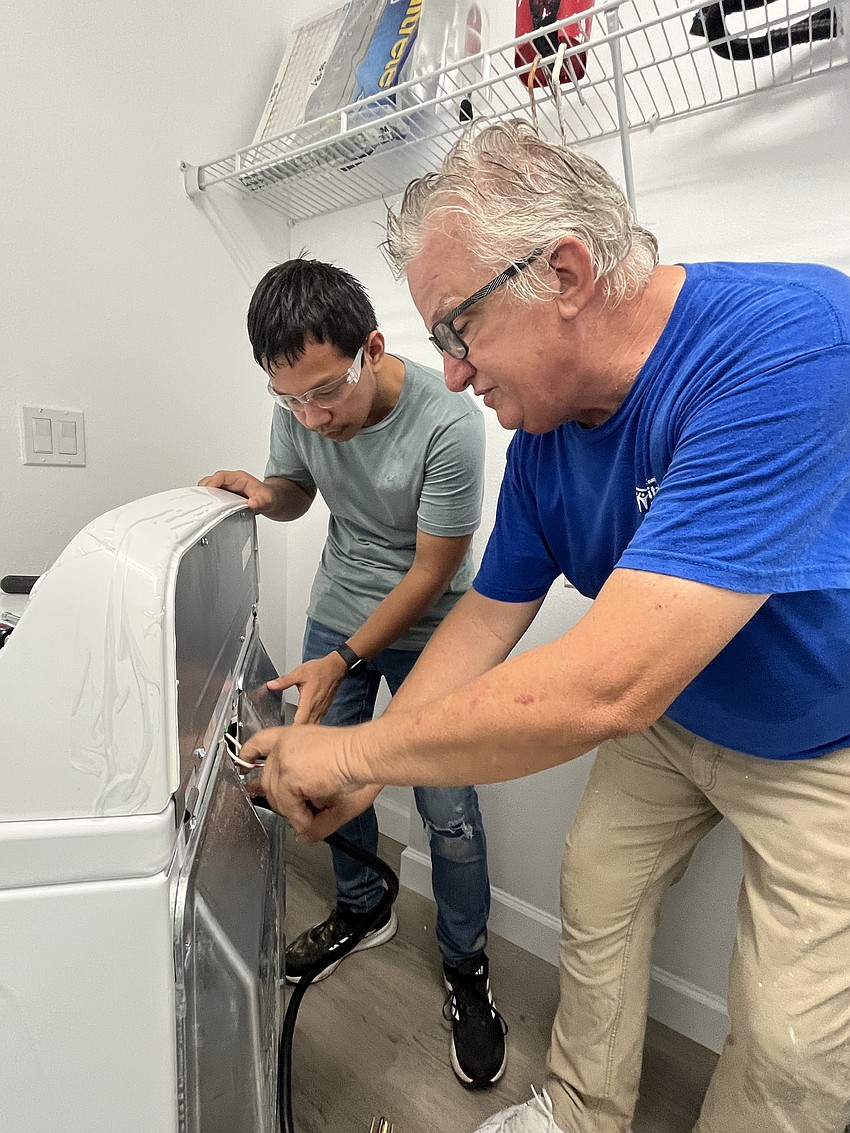 Sophomore Diego Valerio works closely with Pierre Dagenais, the construction supervisor for Manatee County Habitat for Humanity, as they install a washer and dryer.