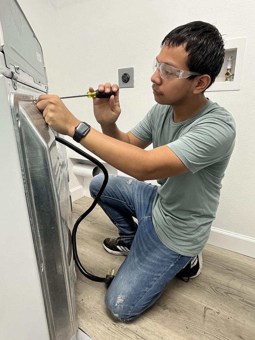 Sophomore Diego Valerio works on installing a dryer. The service project was an opportunity for cadets to learn life skills.