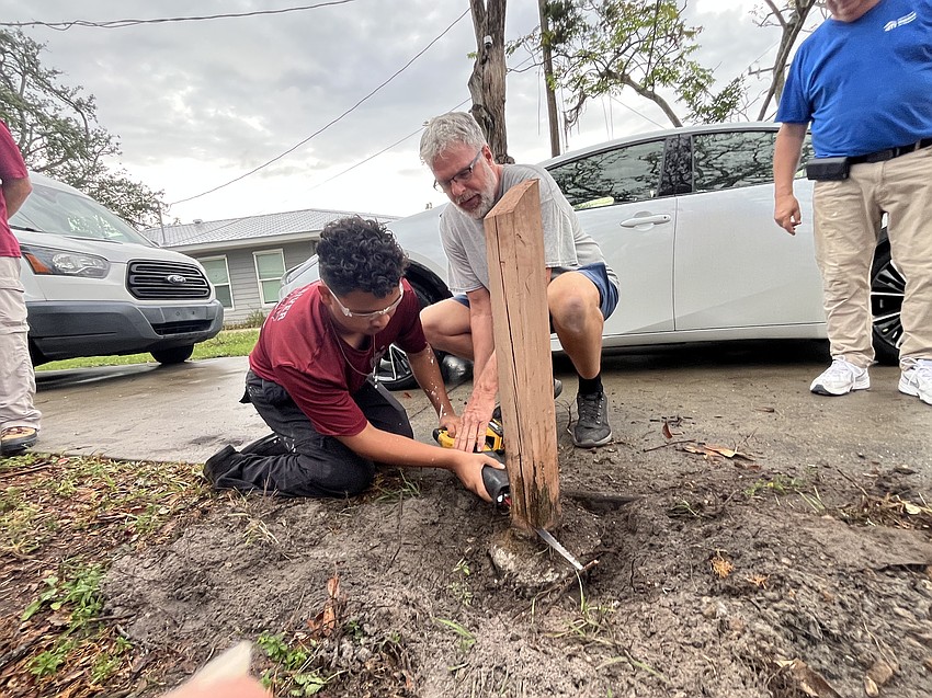 Senior Joshua Bolanos is assisted by Manatee County Habitat for Humanity volunteer Paul Fiechter as he works to take down a fence post.