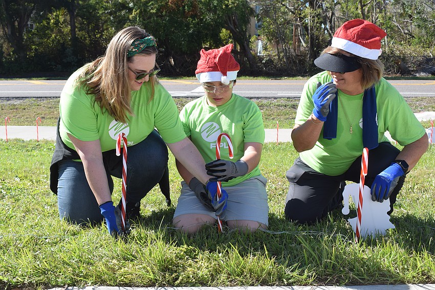 Devaney Iglesias and Rae Dowling teaching Carlos De Armendi how to put in the light-up candy canes safely.