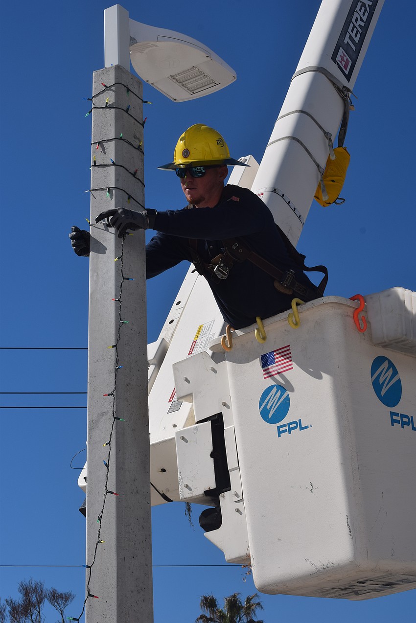 FPL Employee Jordan Thompson stringing up lights around a light pole at the Longboat Key Fire Station.
