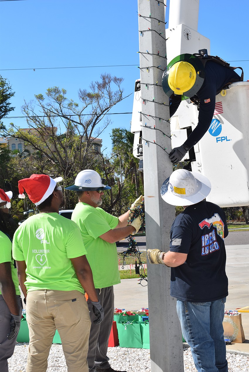 Brett Thompson and Jeffrey Hancock helping Jordan Thompson put up lights at the Longboat Key Fire Station.