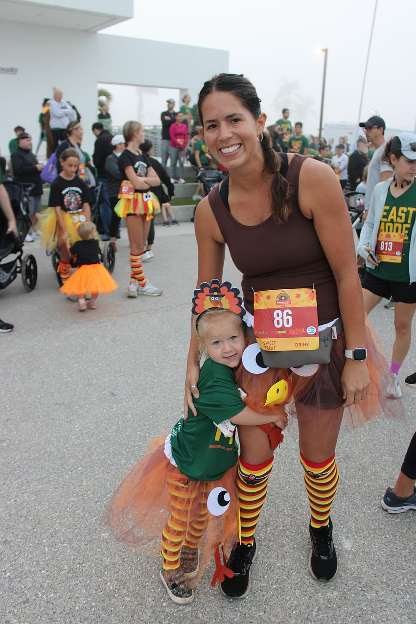 Sarasota's Isabel Munton grabs a turkey leg, or in this case her mom, Marissa Munton, before the Florida Turkey Trot at Nathan Benderson Park.