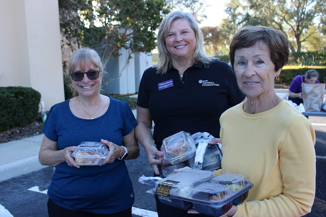 Volunteers Terry Dale and Carol Glider, both of Bradenton, stand on either side of Tidewell Foundation President Delesa Morris as they pack meals during the fifth annual Meal Drive Nov. 27.