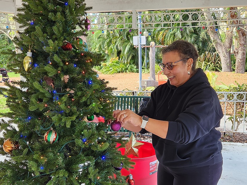 Laurel Park resident Jackie Haywood hangs an ornament on the tree in the gazebo on Saturday, Nov. 30.