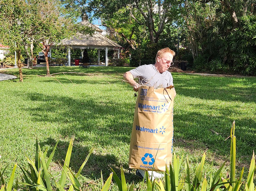 Laurel Park resident Julius Desantis carries a debris bag near the front of the park Saturday, Nov. 30.