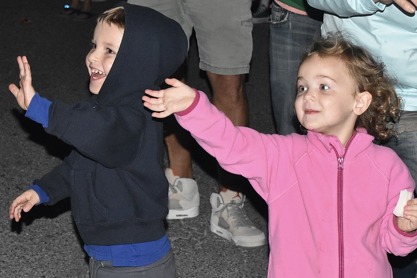 Liam Amstutz and Parker Weathers, 3, wave as Santa Claus approaches.
