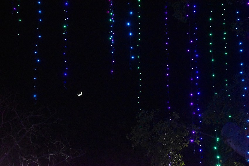 A crescent moon is visible amid strands of lights.