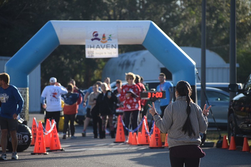 A runner in the Jingle Jog 5K celebrates nearing the finish line on a chilly Saturday morning at The Haven of Sarasota.