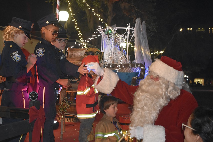 Santa Claus offers gifts to the kids on the Big Cat Habitat float, including Elijah Frey, 8 (second from left).