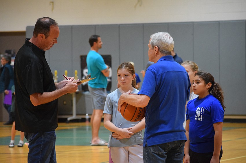 Lakewood Ranch-Sarasota Elks member and volunteer Hoop Shoot scorer Jeff Bosworth (left) and fellow Elks member Randy Volkart (right) go over scoring with the girls 10-11 year-old group at Carlos E. Haile Middle School on Monday, Dec. 9.