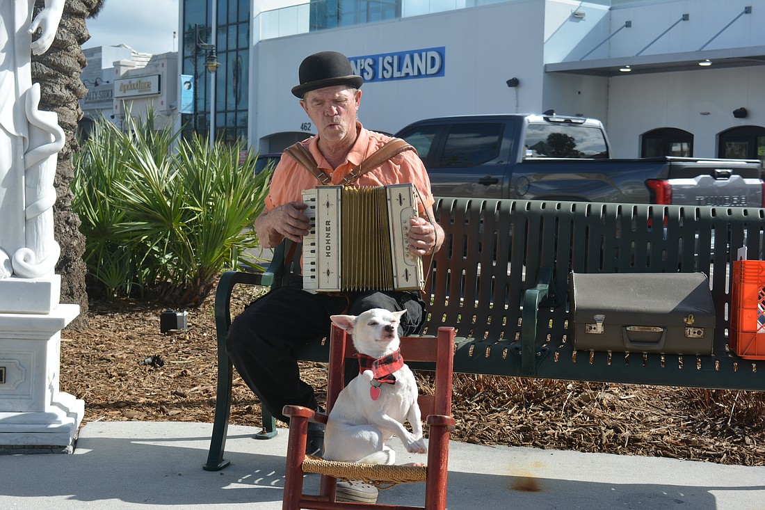 While Birdie McClaine plays his accordion, his companion Lady Haha sits and waits to perform tricks.