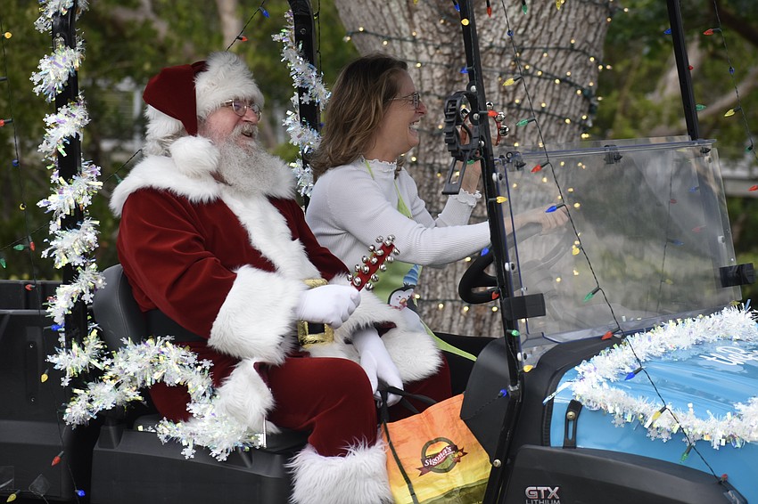 Santa Claus arrives by golf cart with Activation and Program Manager Frances Bermudez.