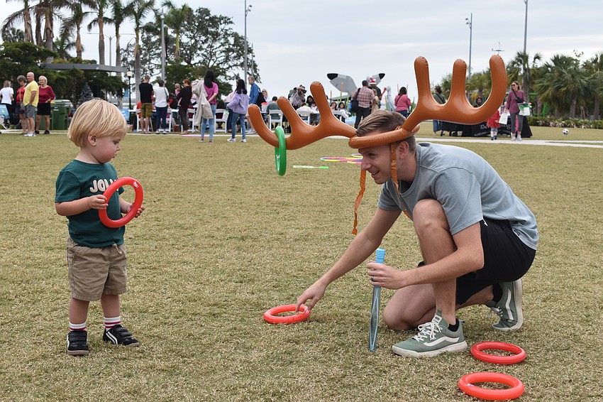 Jude Tomchinsky, 2, and his father David Tomchinsky play the ring toss game.