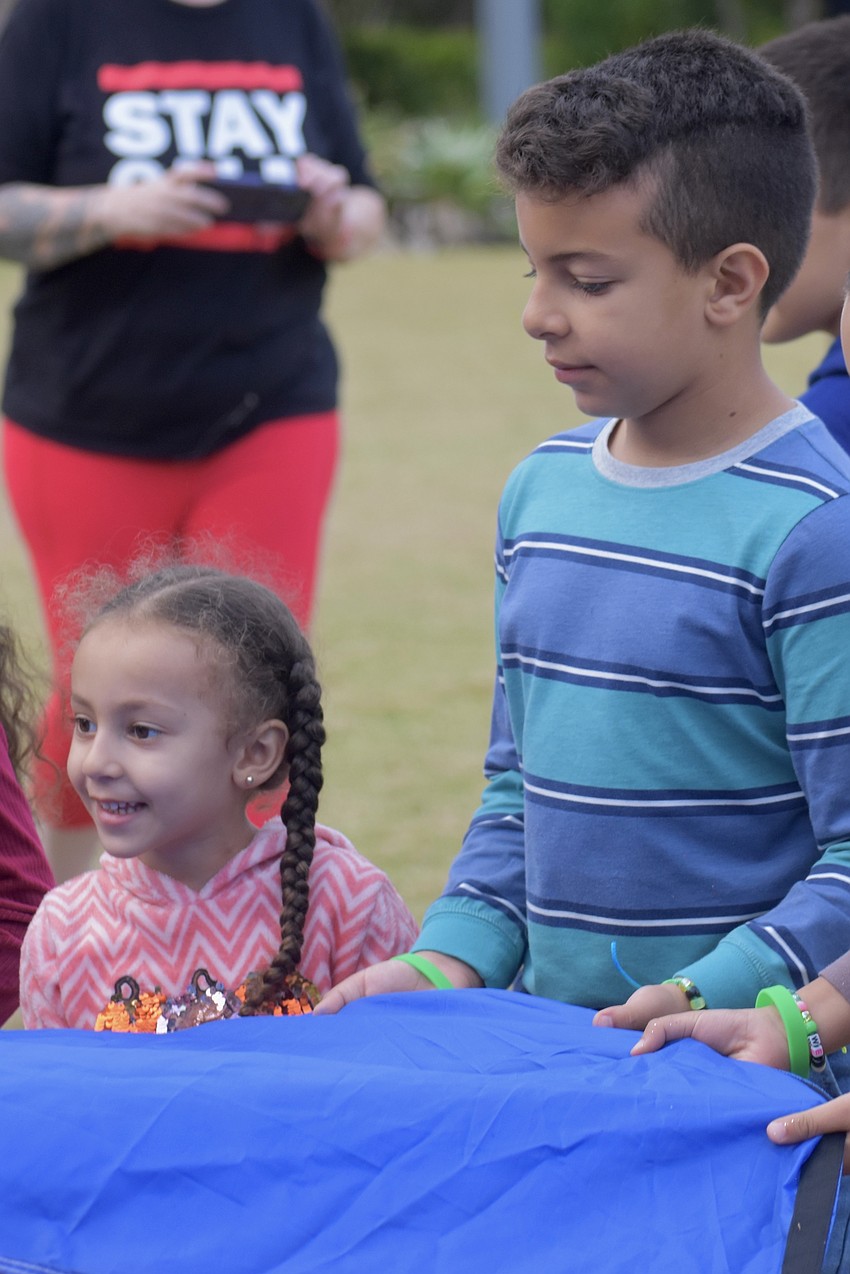 Rachel Abdelmaseh, 3, and her brother Youssef Abdelmaseh, 8, help unfurl a parachute during the activity with Mr. Stevey.