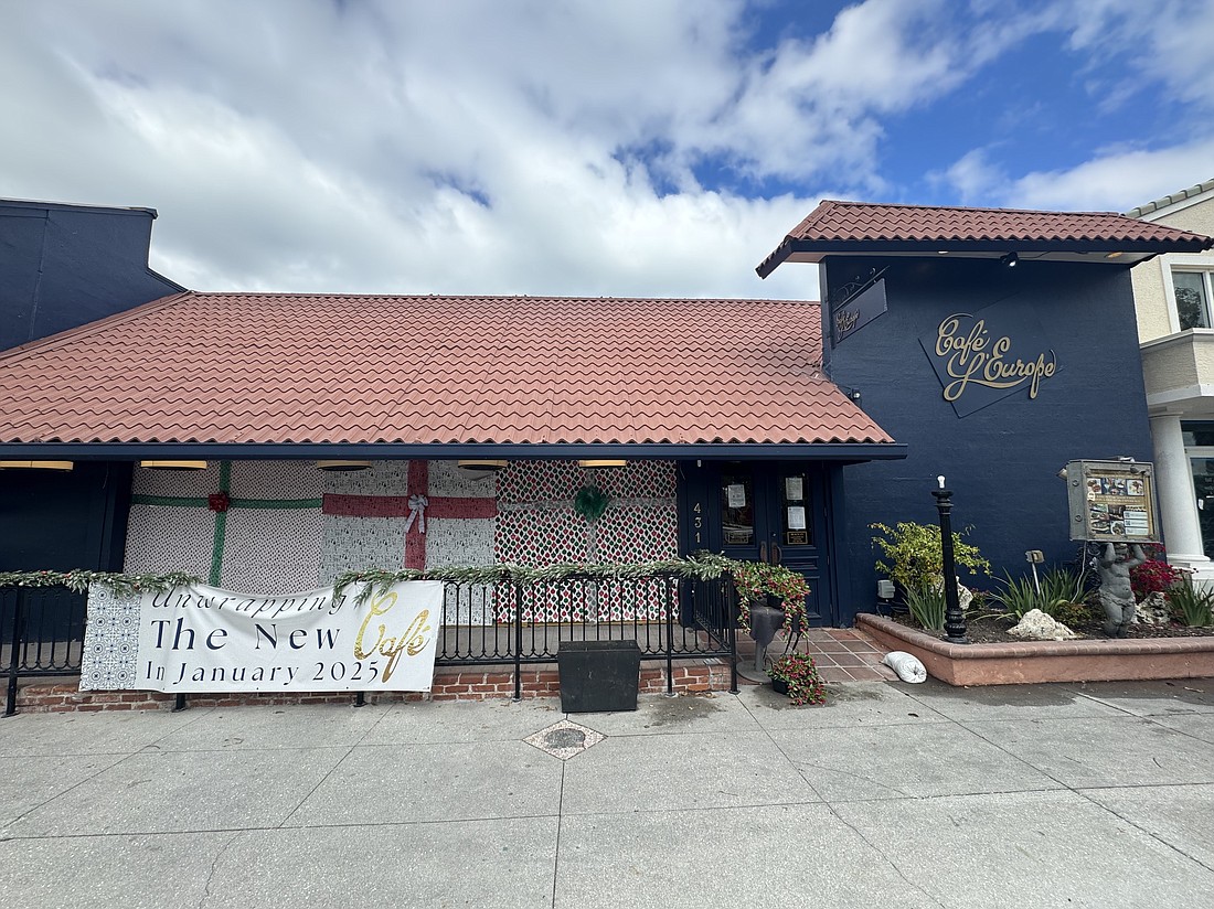 What looks like wrapping paper covers the windows at Cafe L'Europe, where a banner says: "Unwrapping the new cafe in January 2025."