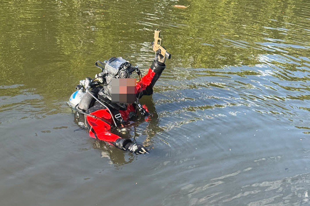 A member of the SPD Underwater Search and Recovery Team, whose identity is concealed, with the recovered firearm tossed into Whitaker Bayou by a fleeing teen arrested in connection with a string of e-bike thefts.