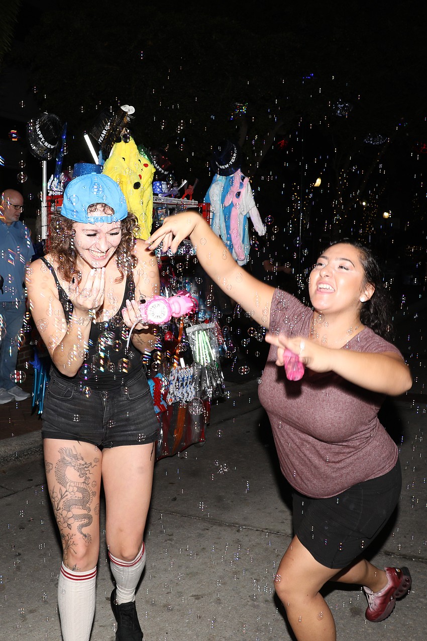 McKenna Shank and Michaela Hope play in the bubbles that fill the air over Main Street in Sarasota on New Year's Eve.