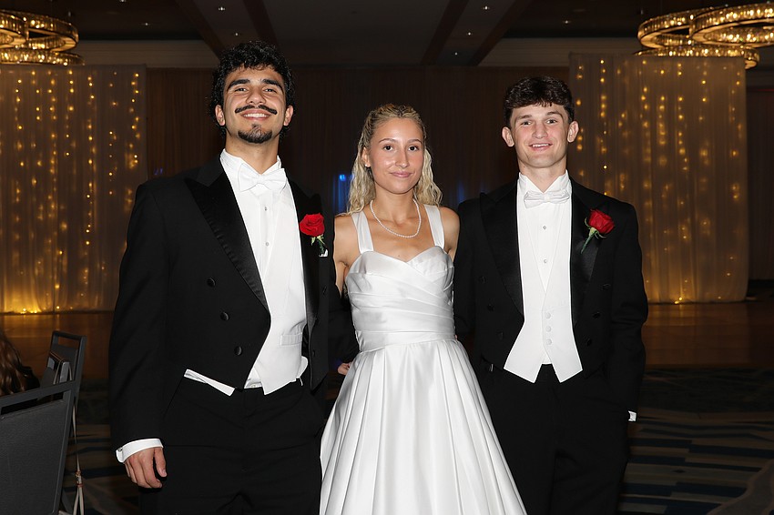 Debutante Maggie Mays is escorted by Rodrigo Berrios and Charles Lambert.