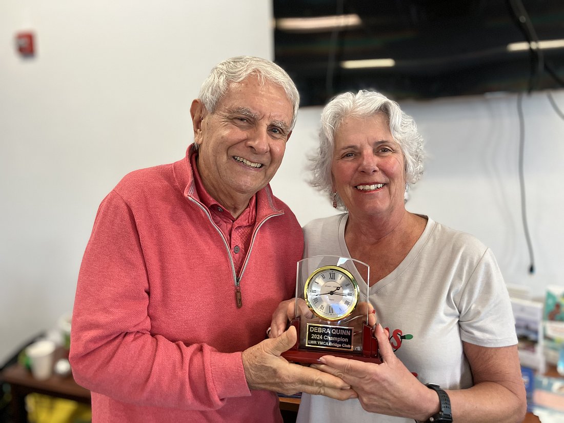 Former champion Ron Orlando hands Debra Quinn the 2024 YMCA Bridge Club trophy on Dec. 19 at the annual potluck luncheon.