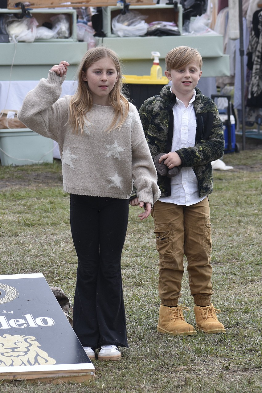 Harper Lassiter, 10, and Jackson Lassiter, 8, play cornhole with their family.