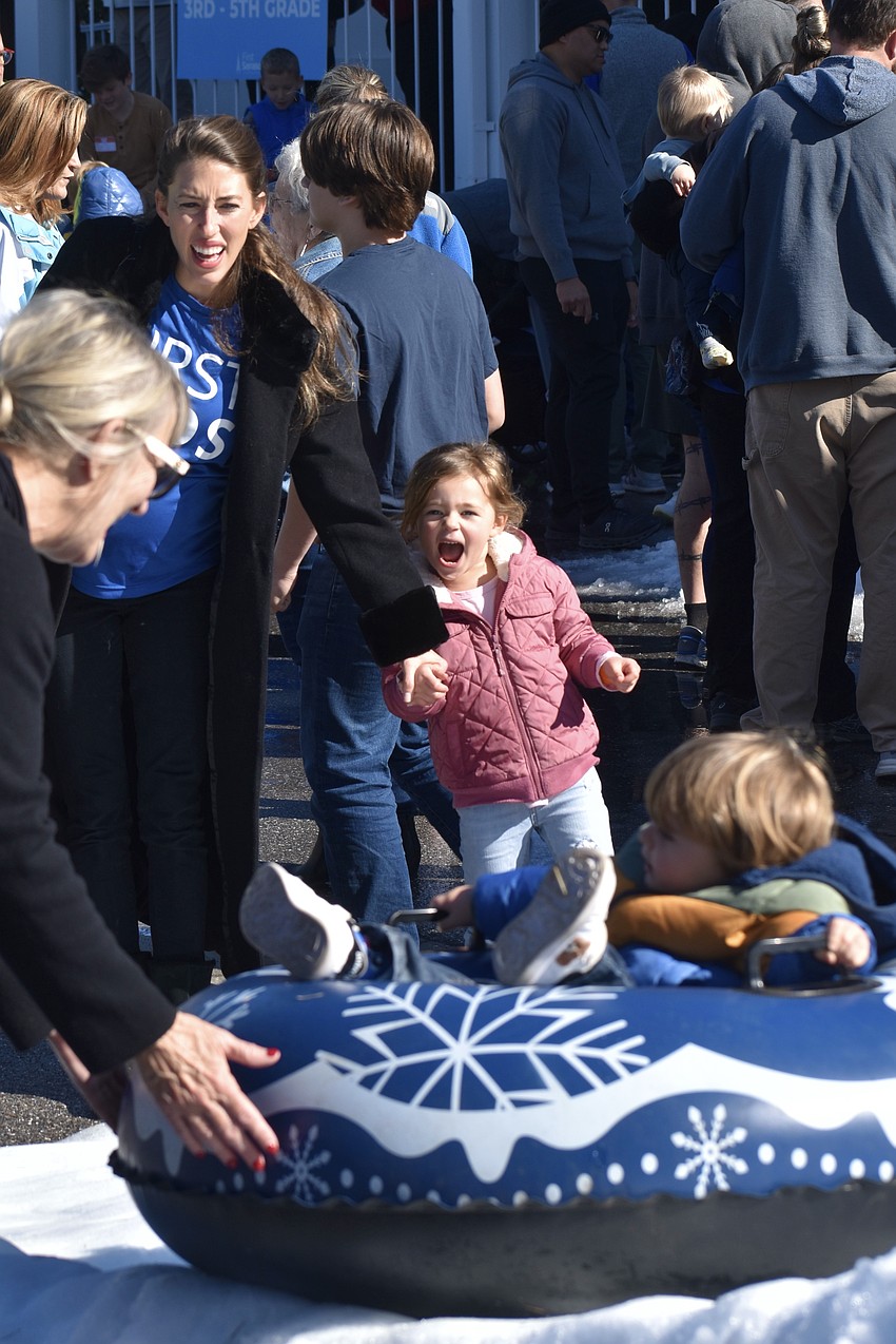 Volunteer Roni Smith assists as Whitney Livingston, and her daughter Lynne Livingston, 4, watch their son and brother RJ Livingston, 2, descend the slide.