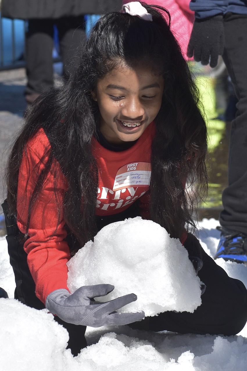 Aanya Likhitesh, 10, scoops up snow to make a snowman.