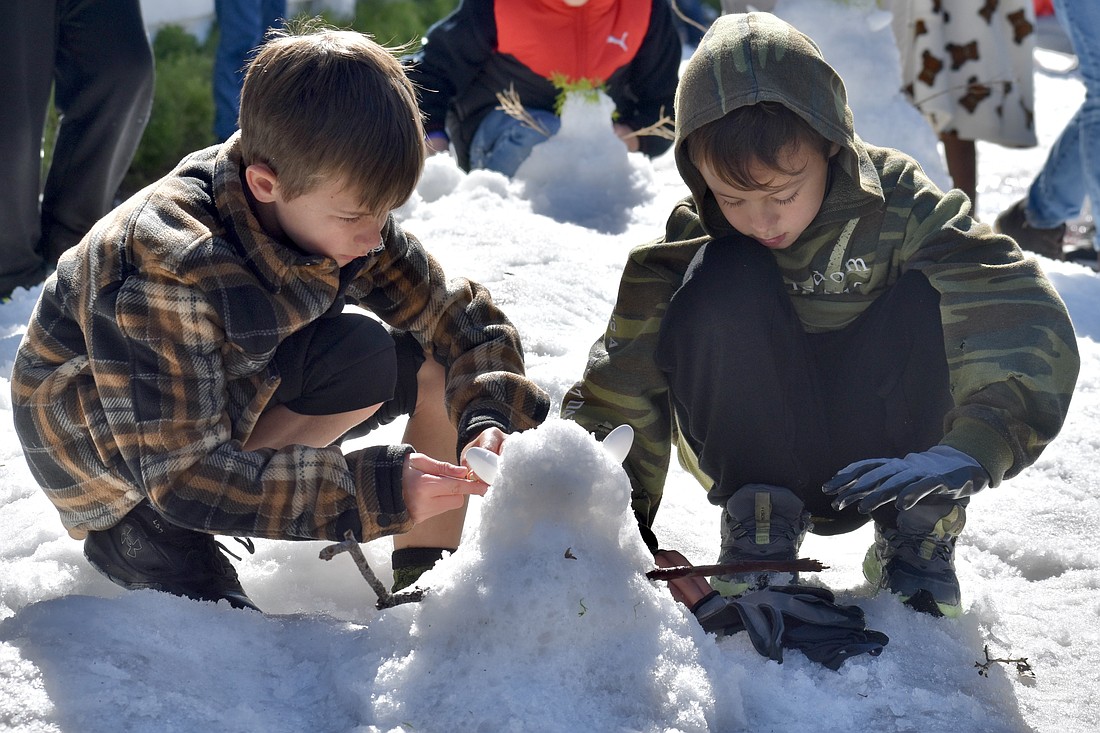 Weston Schurr, 8, and his brother Parker Schurr, 6, build a snowman.