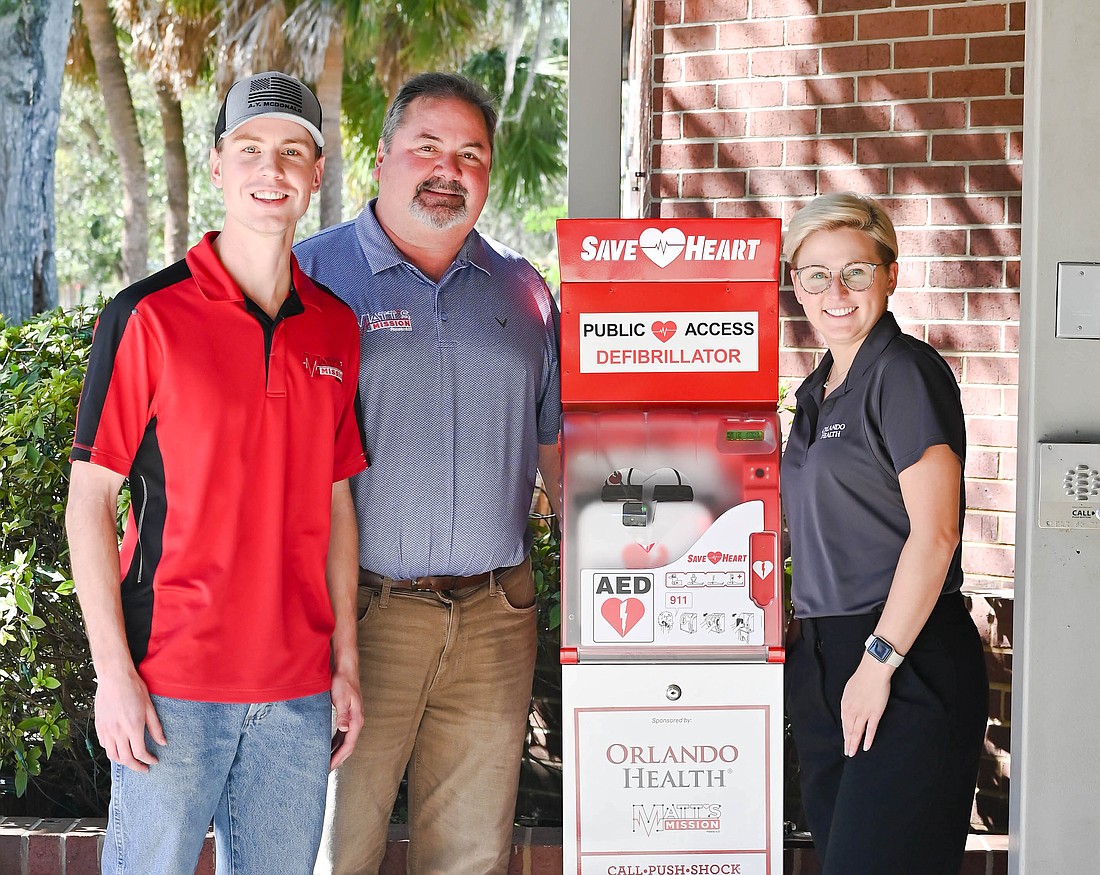 Matt Cobb, left, and his father, Joe Cobb, with a representative from the Winter Garden Fire Rescue Department stand with one of the donated AED towers.