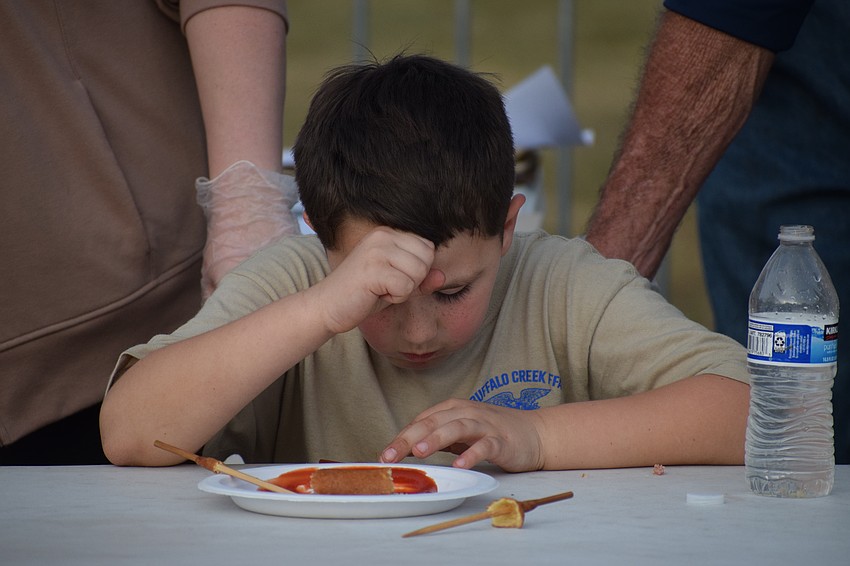 John Myers, 7, takes a moment to collect himself after eating three corndogs in 10 minutes to win the 7-to-10 year-old corndog eating contest at the Manatee County Fair on Saturday.