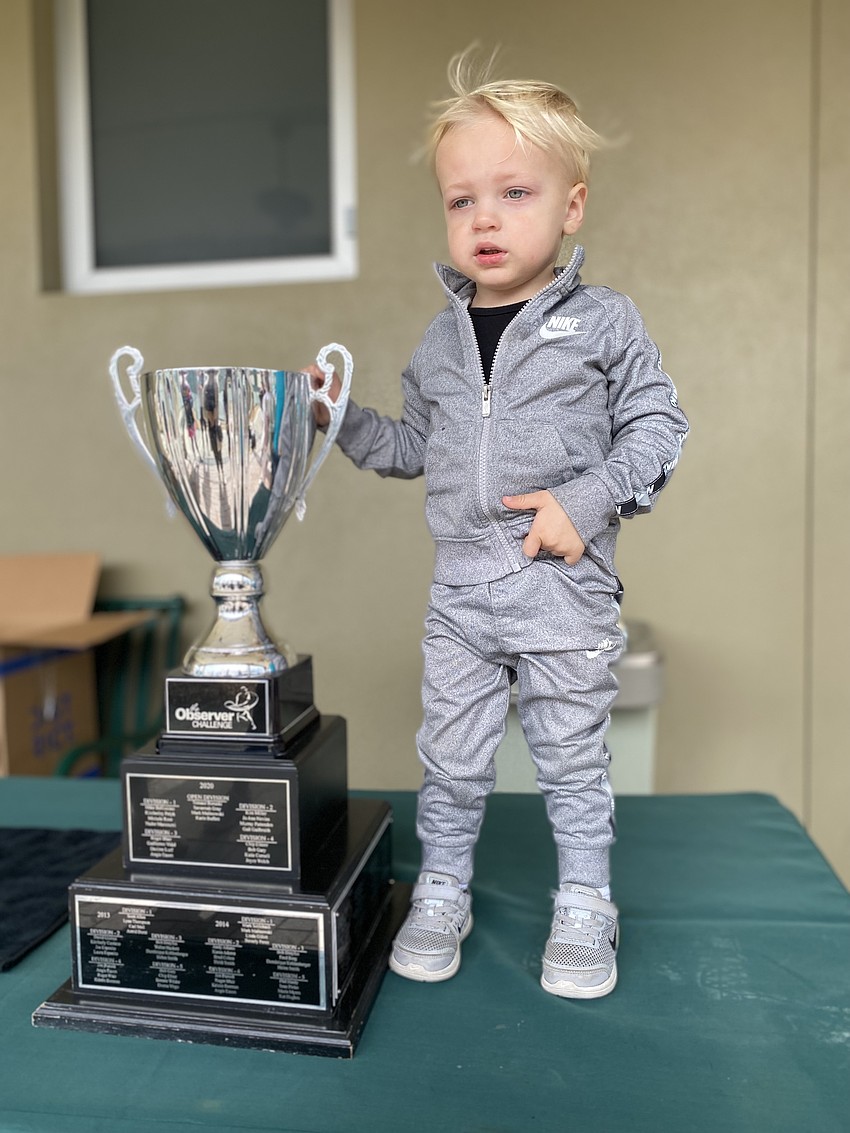 Thomas Herke, son of open division winner Andre Herke, poses for a photo with the trophy.