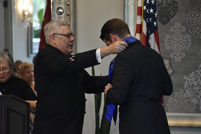 Barry Rush offers a ribbon to outgoing commander Austin Dickinson.