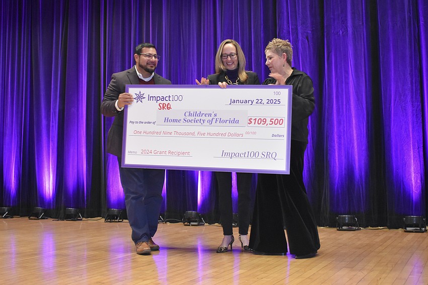 Jessie Garcia and Summer Pfeiffer of Children's Home Society of Florida accept the check from Nancy Platkin.