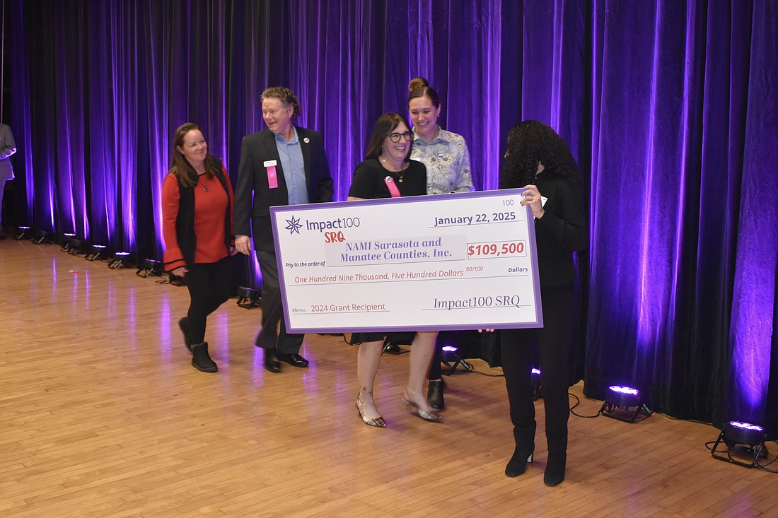 Jessica Polk, Jake Hartvigsen, Colleen Thayer and Beth Walters of Nami prepare to accept the check from Sara Winer.