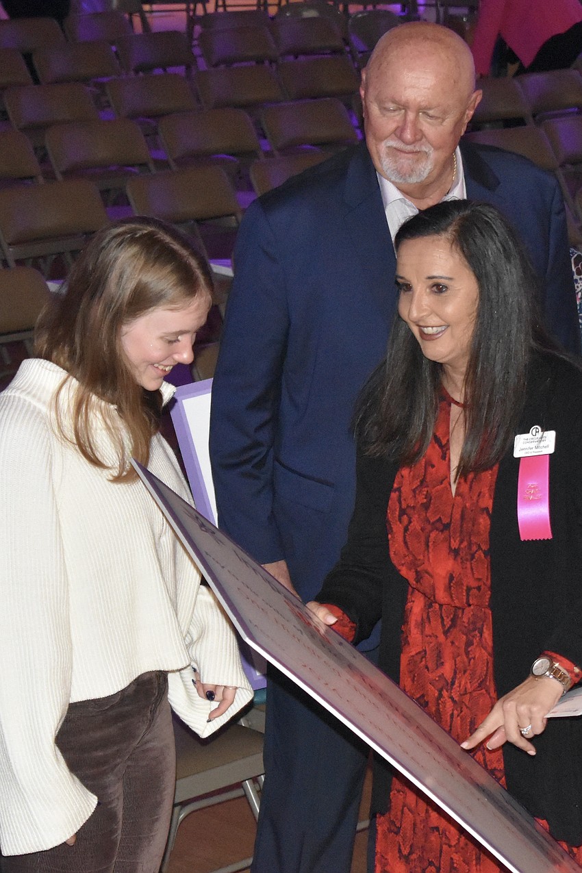 Senior Emma Schwarzbauer, Zoltan Karpathy and Jennifer Mitchell of The Circus Arts Conservatory look over the check.