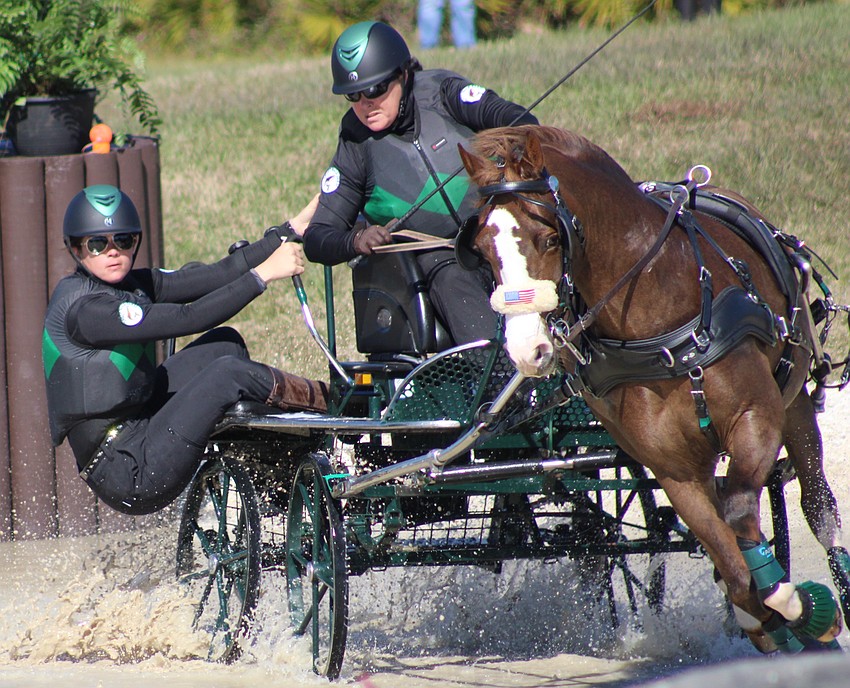 Navigator Sierra Inabnett balances the carriage in a turn as driver Amy Cross, a 2024 national champion in Single Pony, works through a water hazard during the Combined Driving at TerraNova event Saturday in Myakka City.