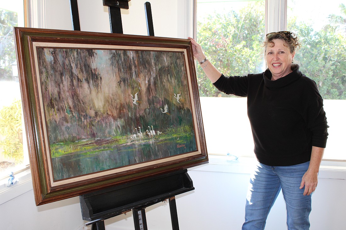 Linn Torres, All Angels by the Sea administative assistant and art sale coordinator, shows one of the pieces that will be available at the 'New to You' art sale starting Feb. 3.