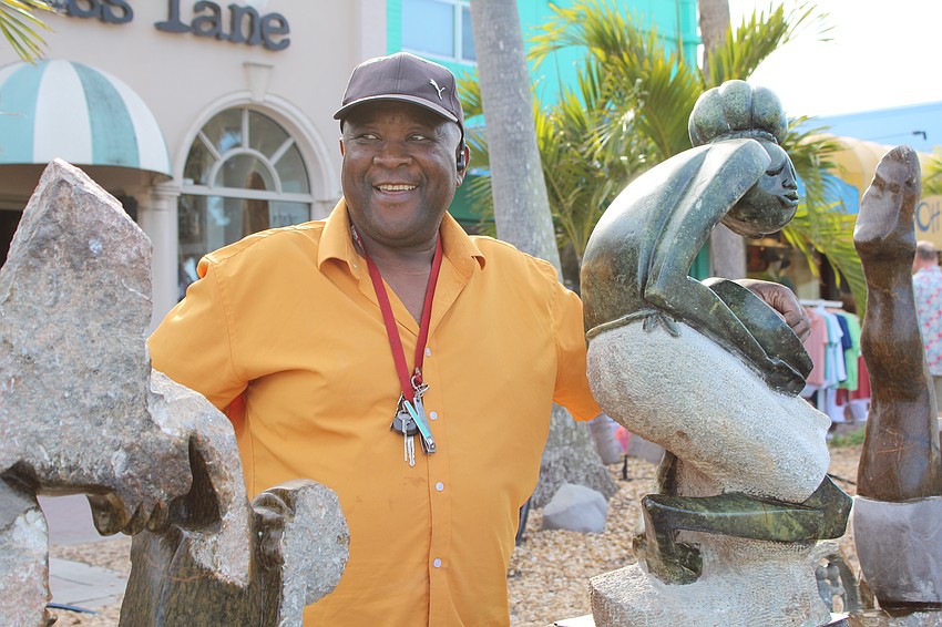Artist Peter Rujuwa smiles next to his sculpture 