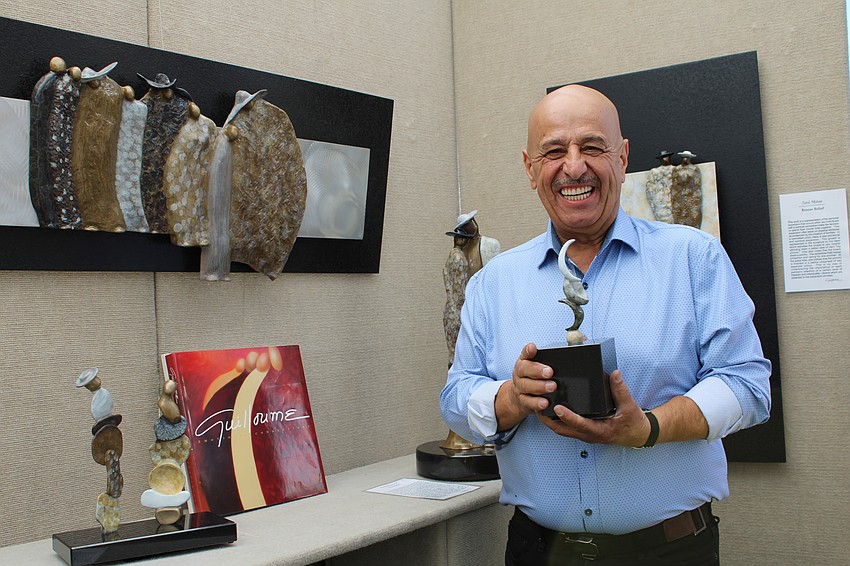 Sculptor Guilloume holds up his work.