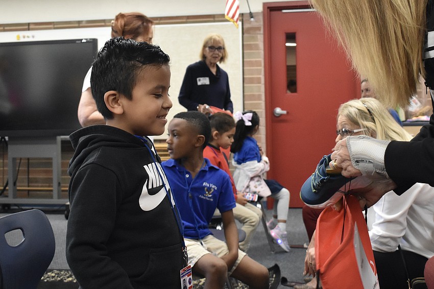 Kindergartener Briseno-Juarez watches as Dawn Merila places his new shoes into a bag.