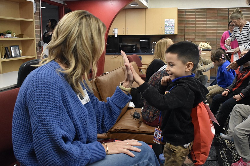 Tina Russell offers a high-five to kindergartener Leonardo Gomez-Flores as he walks away with a pair of shoes.